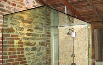 Glass shower enclosure showing tile work and plumbing fixtures